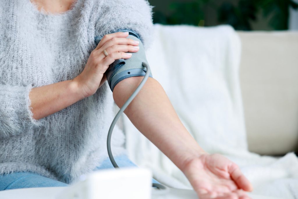 Eine Person misst den Blutdruck mit einem Blutdruckmessgerät